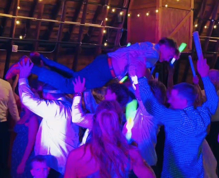 Guests crowd surfing under DJ ANIMALE lighting at the Warrick Wedding