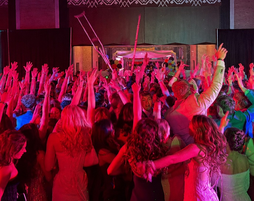 Hundreds of students with hands raised at Omaha Westside Prom